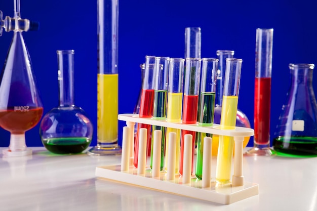 Chemistry lab equipment on a table over blue background. Glassware and biology equipment