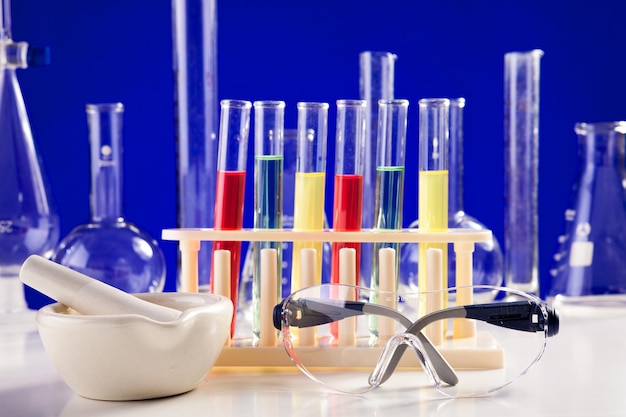 Chemistry lab set on a table with protective eyeglasses over blue background. glassware and biology equipment