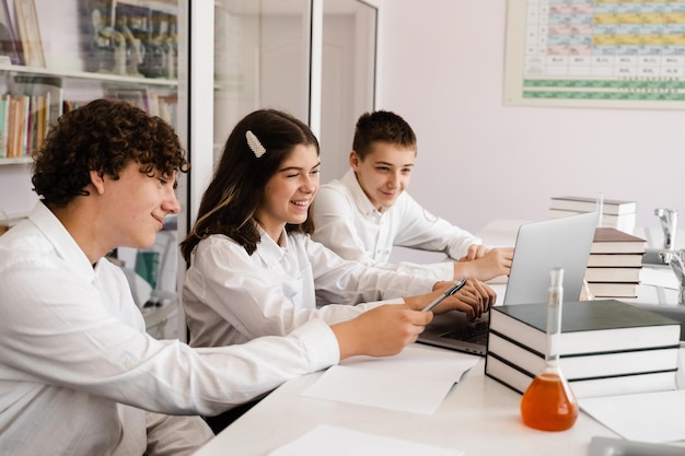 Chemistry lesson in labaratory education online in class with\
group of pupils studying on laptop smiling and having fun\
together