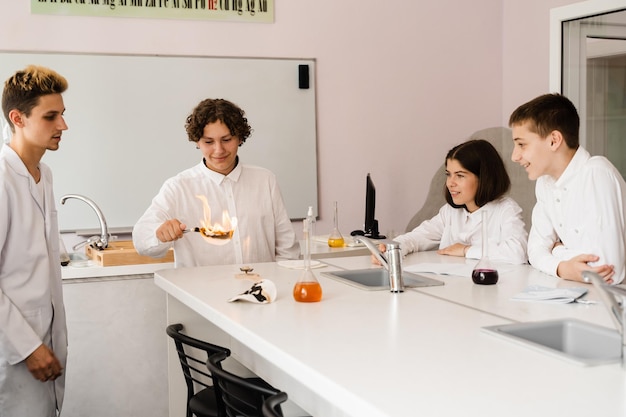 Chemistry lesson in labaratory Education online in class with group of pupils studying on laptop smiling and having fun together