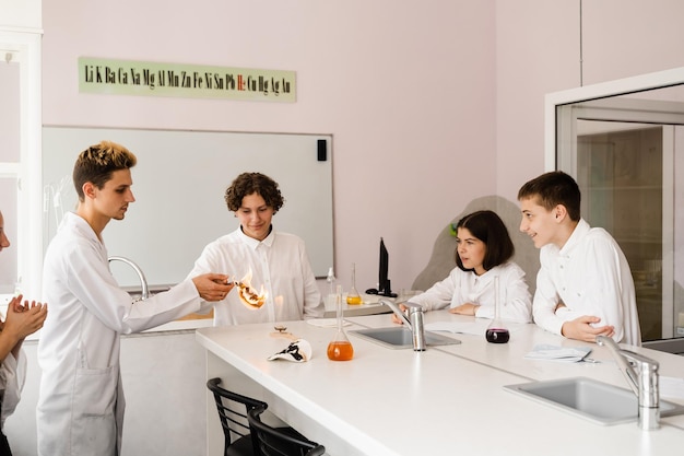 Chemistry lesson in labaratory Education online in class with group of pupils studying on laptop smiling and having fun together