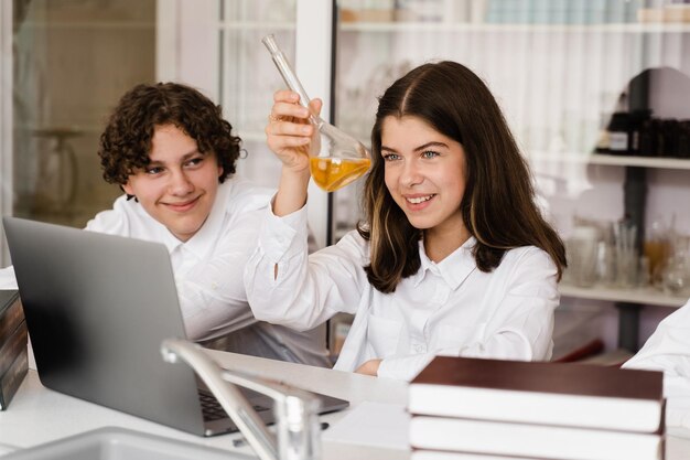 Chemistry lesson Schoolgirl and classmates holds flask for experiments and smiles in the laboratory School education