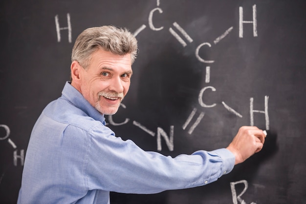 Chemistry writes on the blackboard formula in University.