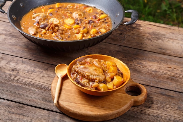 Cheolnt in a large frying pan and a plate on a wooden board on the table