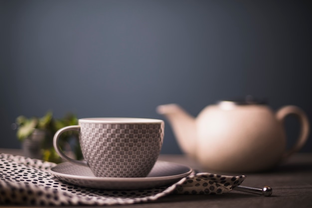 Tazza di tè modello a scacchi su tessile punteggiata a pois sul tavolo