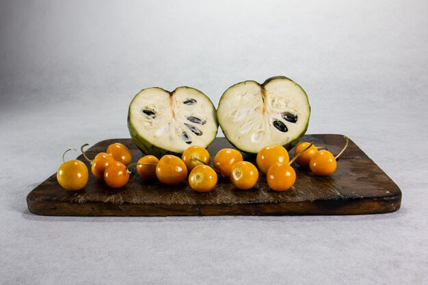 cherimoya y uchuva aguaymanto  uvilla exotic peruvianlatin american fruit sits on a brown wooden board and white background with shadows