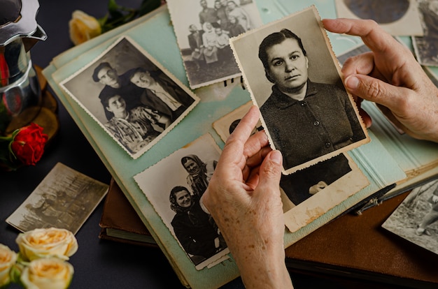 Cherkasy / Oekraïne - 12 december 2019: vrouwelijke handen houden en oude foto van haar moeder. Vintage fotoalbum met foto's. Familie en levenswaarden concept.