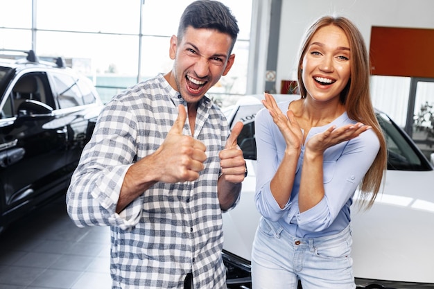 Foto allegra giovane coppia presso la concessionaria che acquista una nuova auto