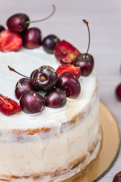 写真 ココナッツのチーズケーキの上に食べられる金色のチェリーとイチゴ