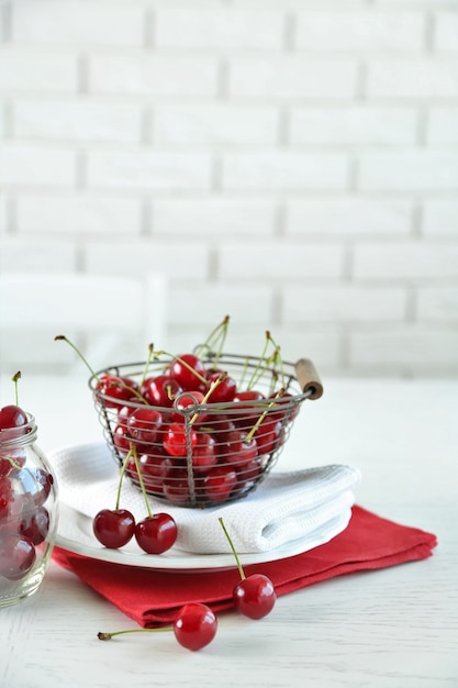 Cherries in basket on table, on light