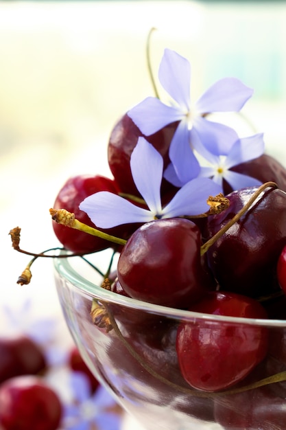 Cherries and flowers in a transparent glass vase.