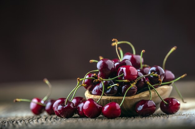 Cherries. Fresh sweet cherries. Delicious cherries with water drops in retro bowl on old oak table.