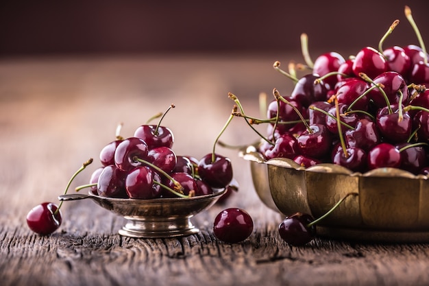 Cherries. Fresh sweet cherries. Delicious cherries with water drops in retro bowl on old oak table.