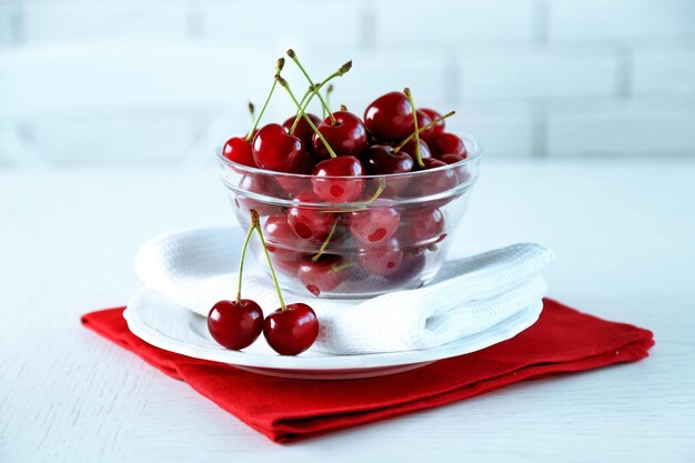 Photo cherries in glass bowl on table on light background