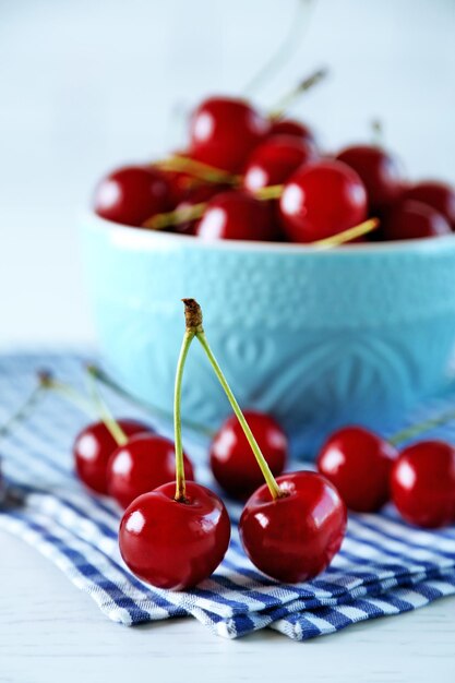 Cherries in mug on table on light background