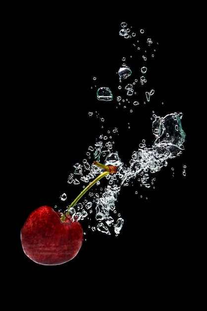 さくらんぼは、新鮮な飲み物の広告のための黒い背景に水に飛び散る