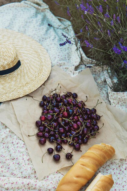 Cherry berries and baguette on the blanket during picnic in the lavender field