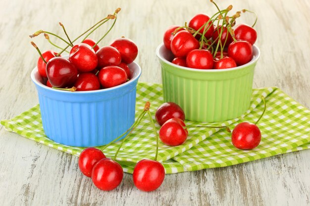 Cherry berries in bowls on wooden table close up