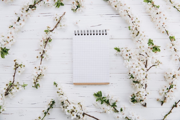 Cherry blossom and empty notebook on white wooden table