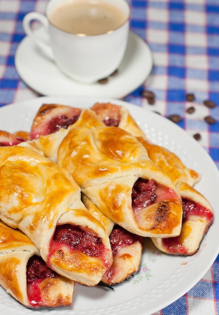 cherry bun on a plate and cup of coffee