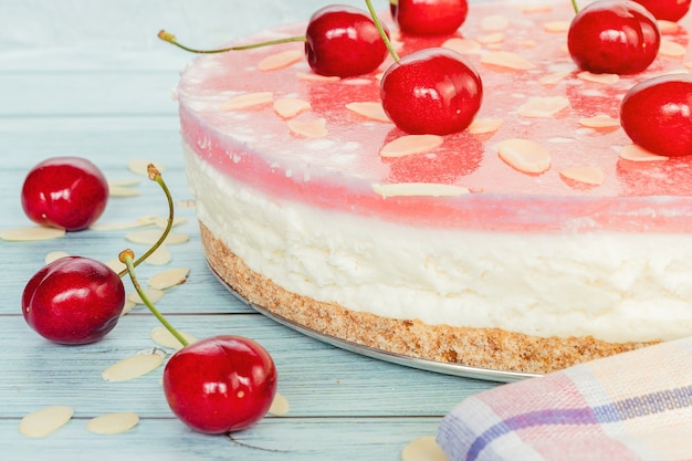 Cherry cheesecake close-up on a light wooden surface, layers of dessert