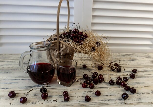 Cherry and cherry juice or wine on a wooden table a decanter and a glass with juice