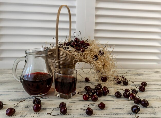 Cherry and cherry juice or wine on a wooden table a decanter and a glass with juice