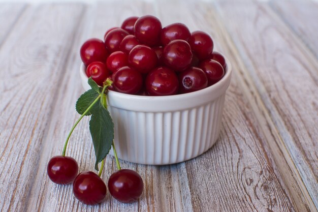 Cherry. Cherry in a white ceramic cup on an old wooden surface.