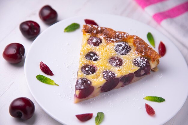 Cherry clafoutis is a baked French fruit dessert, traditionally black cherries, arranged on a butter