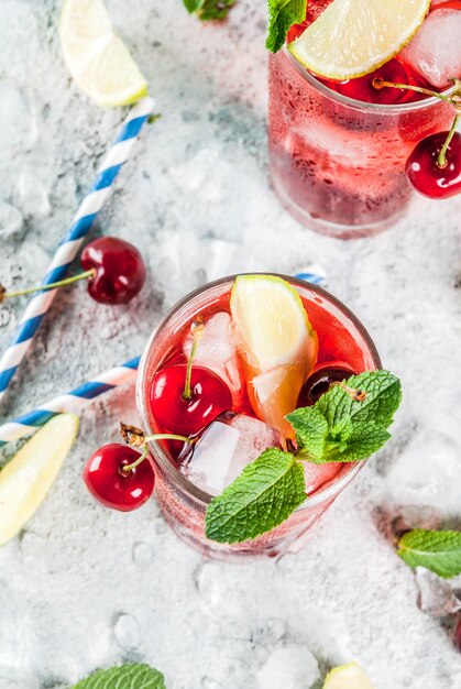 Foto mojito di ciliegia cola in bicchiere alto con foglie di menta