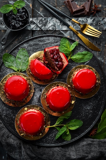 Cherry creammousse dessert with cherries and mint on a black stone plate Top view Rustic style