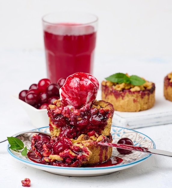 Cherry crumble pie decorated with a scoop of ice cream and drizzled with cherry sauce