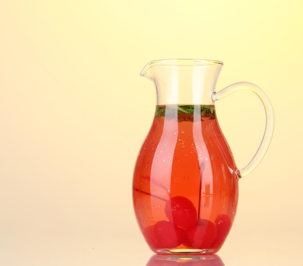 Cherry drink in pitcher on yellow background