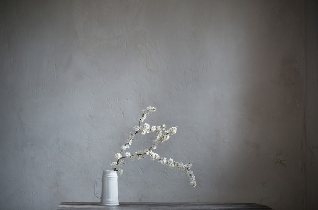 Cherry flowers in white jug on old wooden table