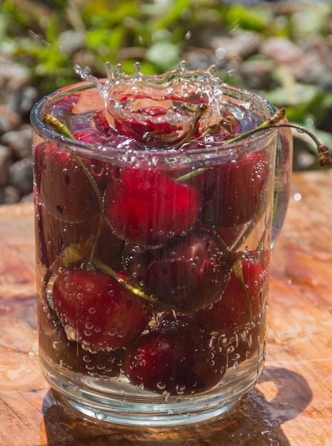 Photo cherry in glass of water and drops.