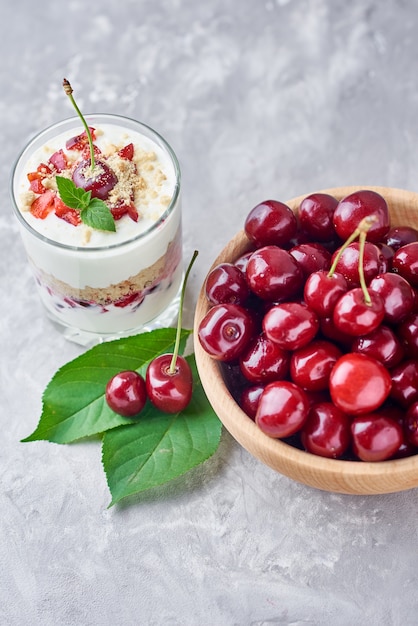 Muesli o frullato di ciliegia in vetro e bacche fresche in una ciotola di legno. colazione salutare