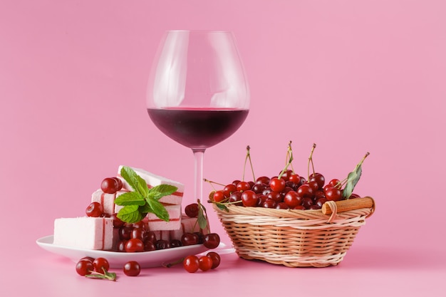 Cherry homemade liquor in a glasses on pink background and cherries