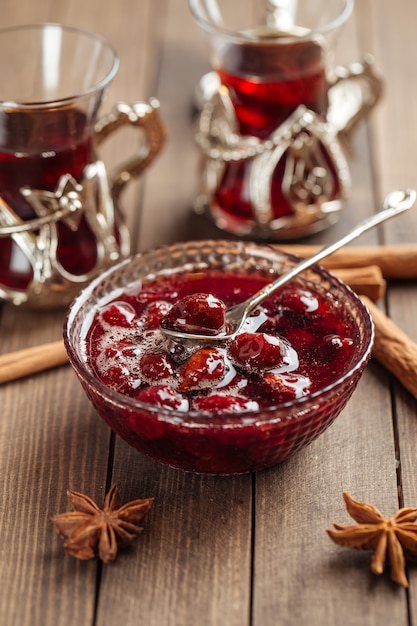 Marmellata di ciliegie in una ciotola di vetro su legno