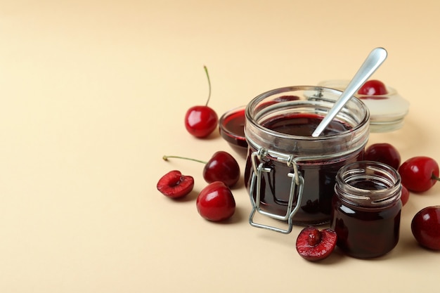 Cherry jam and ingredients on beige background