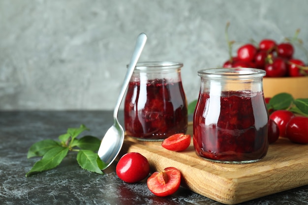 Cherry jam and ingredients on black smokey table