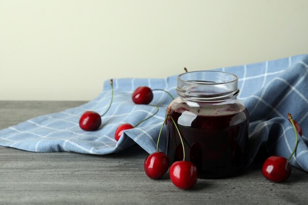 Foto marmellata di ciliegie e ingredienti sul tavolo grigio strutturato