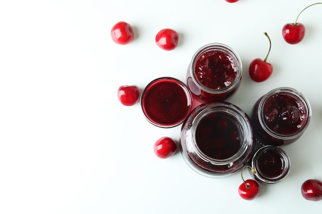 Marmellata di ciliegie e ingredienti su sfondo bianco