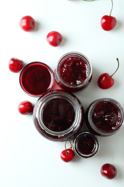 Cherry jam and ingredients on white background