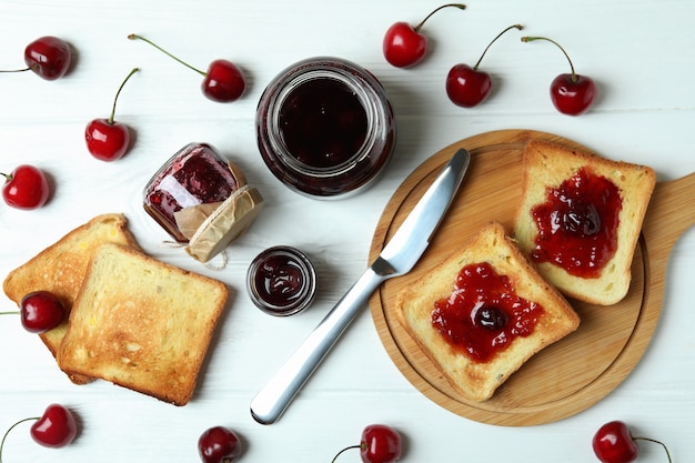 Cherry jam and ingredients on white wooden table