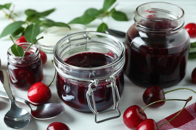 Cherry jam and ingredients on white wooden table