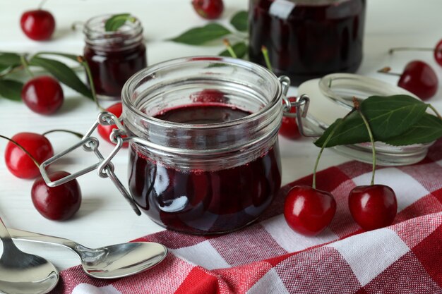 Cherry jam and ingredients on white wooden table
