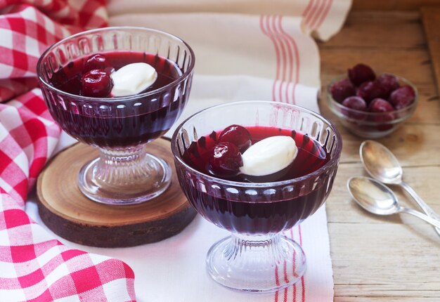 Cherry jelly with cream and berries on a wooden table. Rustic style.