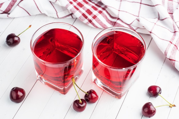 cherry juice in glass glasses with fresh cherry berries. white background. .
