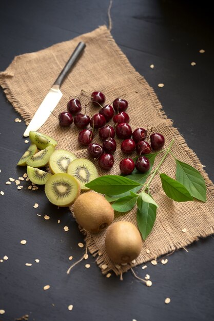 Foto ciliegia, kiwi e su tela di sacco e tavolo in legno scuro