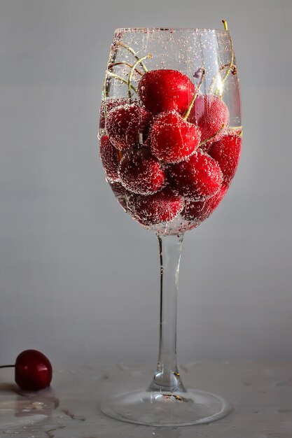 cherry lies in a glass close up, bubbles on a cherry